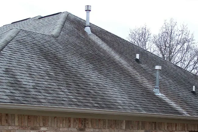 An asphalt shingle roof covered in dark black algae streaks and organic growth before a low-pressure soft washing treatment service in Appleton, Wisconsin.